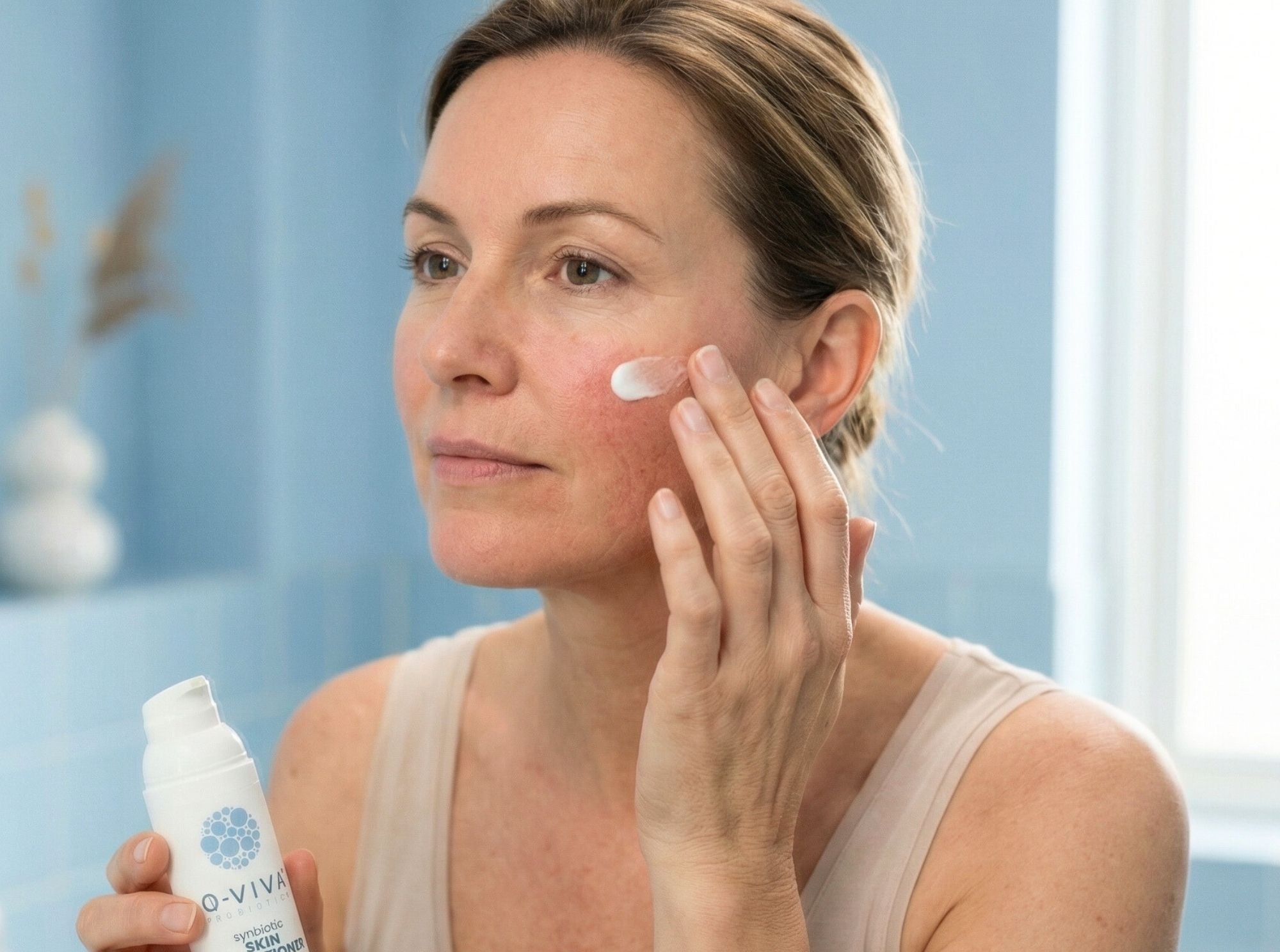 Vrouw die Q-Viva Skin Conditioner op haar gezicht aanbrengt als onderdeel van een milde dagelijkse huidverzorgingsroutine