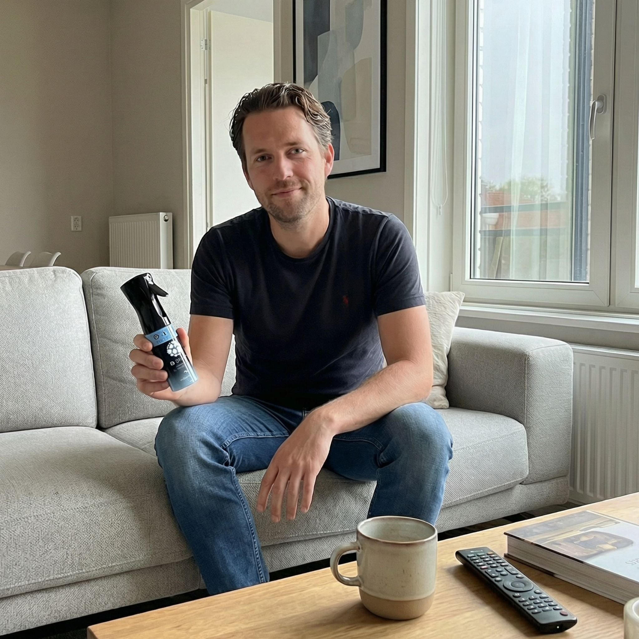 Man zit op een bank met Q-Viva Allergen Spray en toont gebruik op huishoudtextiel voor vrijer ademen