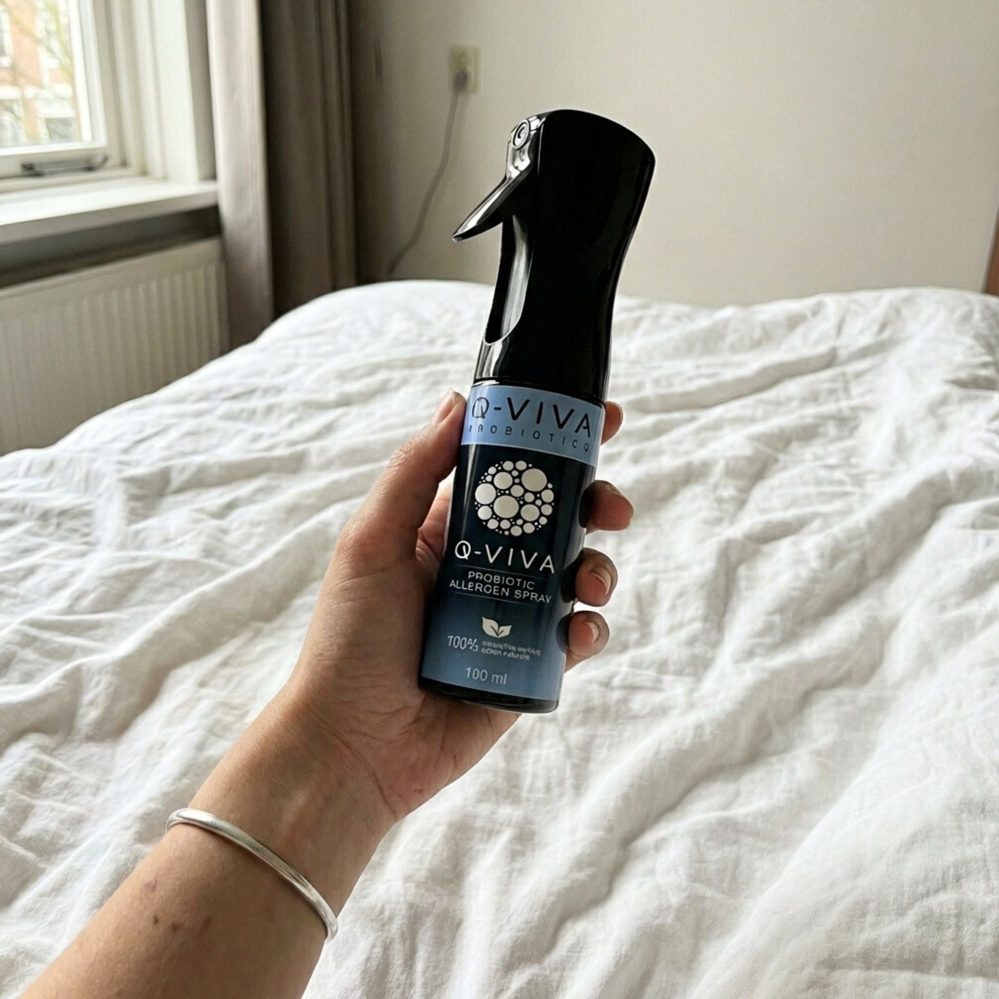 Persoon houdt Q-Viva Allergen Spray boven beddengoed vast en toont gebruik in de slaapkamer voor een comfortabelere nachtrust